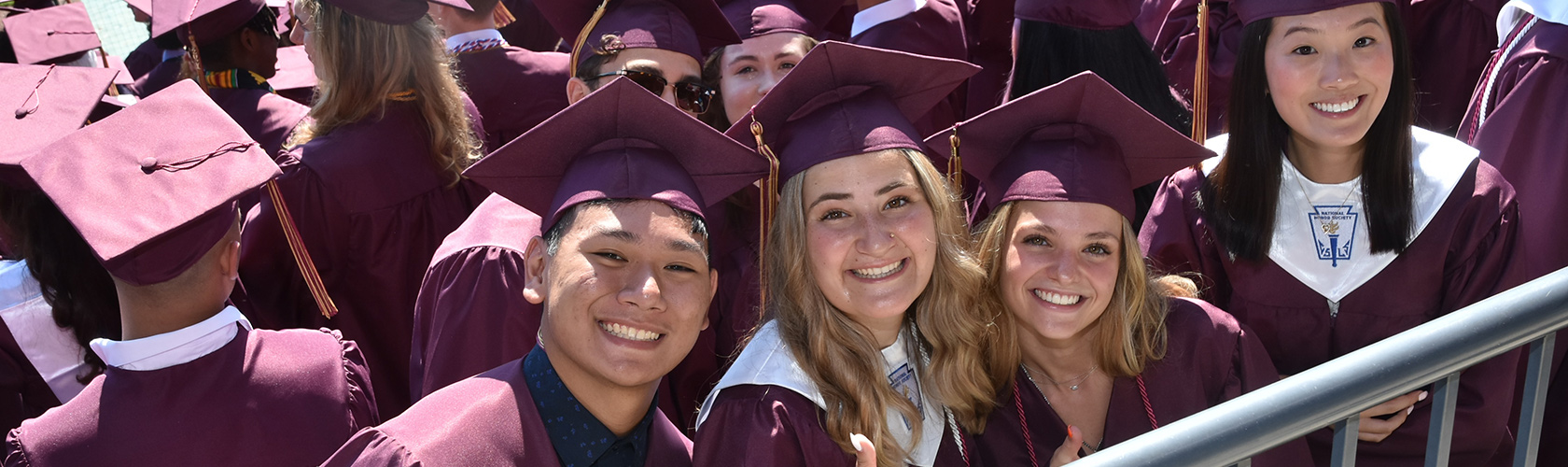 Smiling graduates of New Albany High School in their caps and gowns at graduation.