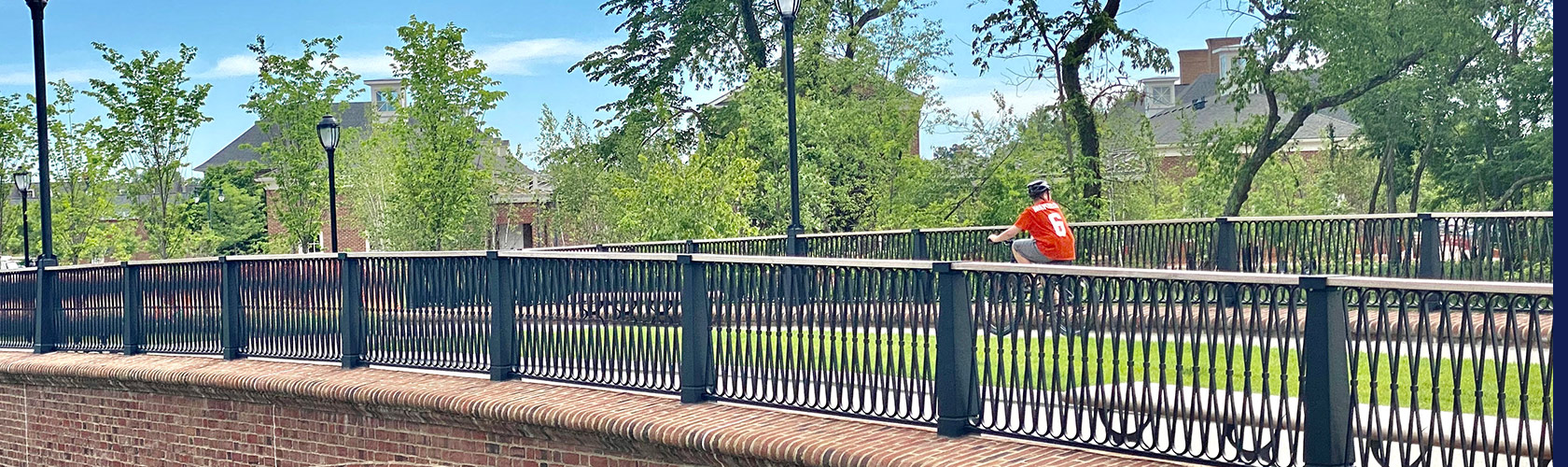 Person riding bike across railed bridge on sunny day in New Albany, Ohio.